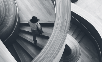 black and white view of an individual on a curved staircase